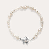 The Flora Multi Pearl Toggle Bracelet in Silver features irregular white freshwater pearls and a sterling silver floral toggle clasp shaped like a butterfly, elegantly displayed on a plain light background.