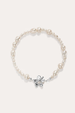 The Flora Multi Pearl Toggle Bracelet in Silver features irregular white freshwater pearls and a sterling silver floral toggle clasp shaped like a butterfly, elegantly displayed on a plain light background.