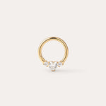 The Crystal Heart Titanium Daith Ring in Gold features a petite gold hoop with a pear-shaped clear gemstone at its center, accented by two round clear stones on each side, shown against a simple light background—ideal for sensitive ears thanks to its hypoallergenic Yellow Gold PVD finish.