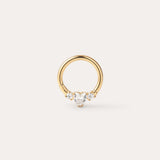 The Crystal Heart Titanium Daith Ring in Gold features a petite gold hoop with a pear-shaped clear gemstone at its center, accented by two round clear stones on each side, shown against a simple light background—ideal for sensitive ears thanks to its hypoallergenic Yellow Gold PVD finish.