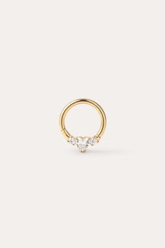 The Crystal Heart Titanium Daith Ring in Gold features a petite gold hoop with a pear-shaped clear gemstone at its center, accented by two round clear stones on each side, shown against a simple light background—ideal for sensitive ears thanks to its hypoallergenic Yellow Gold PVD finish.