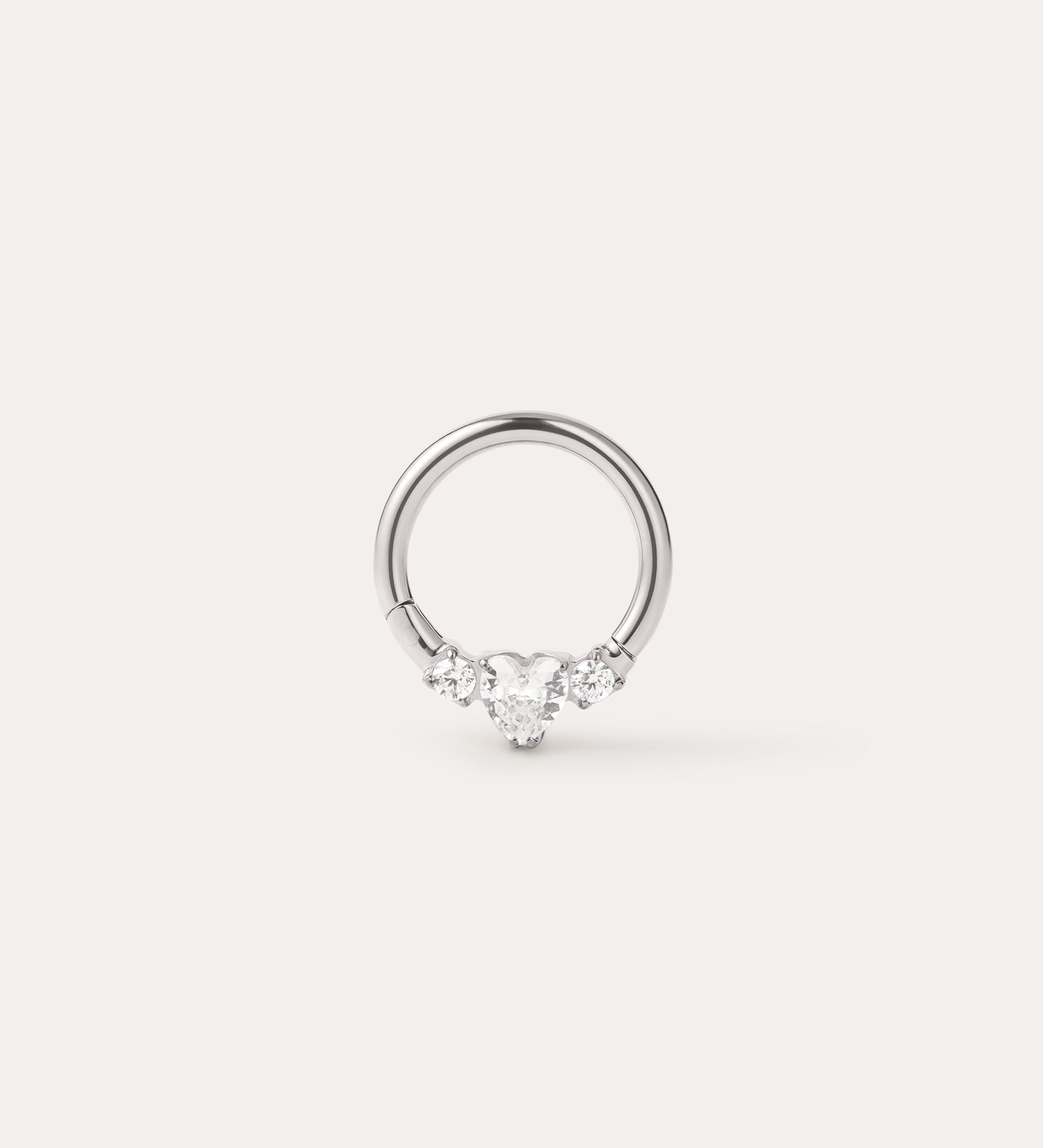 A Crystal Heart Titanium Daith Ring in Platinum, featuring a central heart-shaped gemstone flanked by two smaller round gemstones on each side, displayed on a plain light background. Crafted from implant-grade titanium with a platinum PVD finish, this hypoallergenic daith ring combines elegance with comfort for everyday wear.