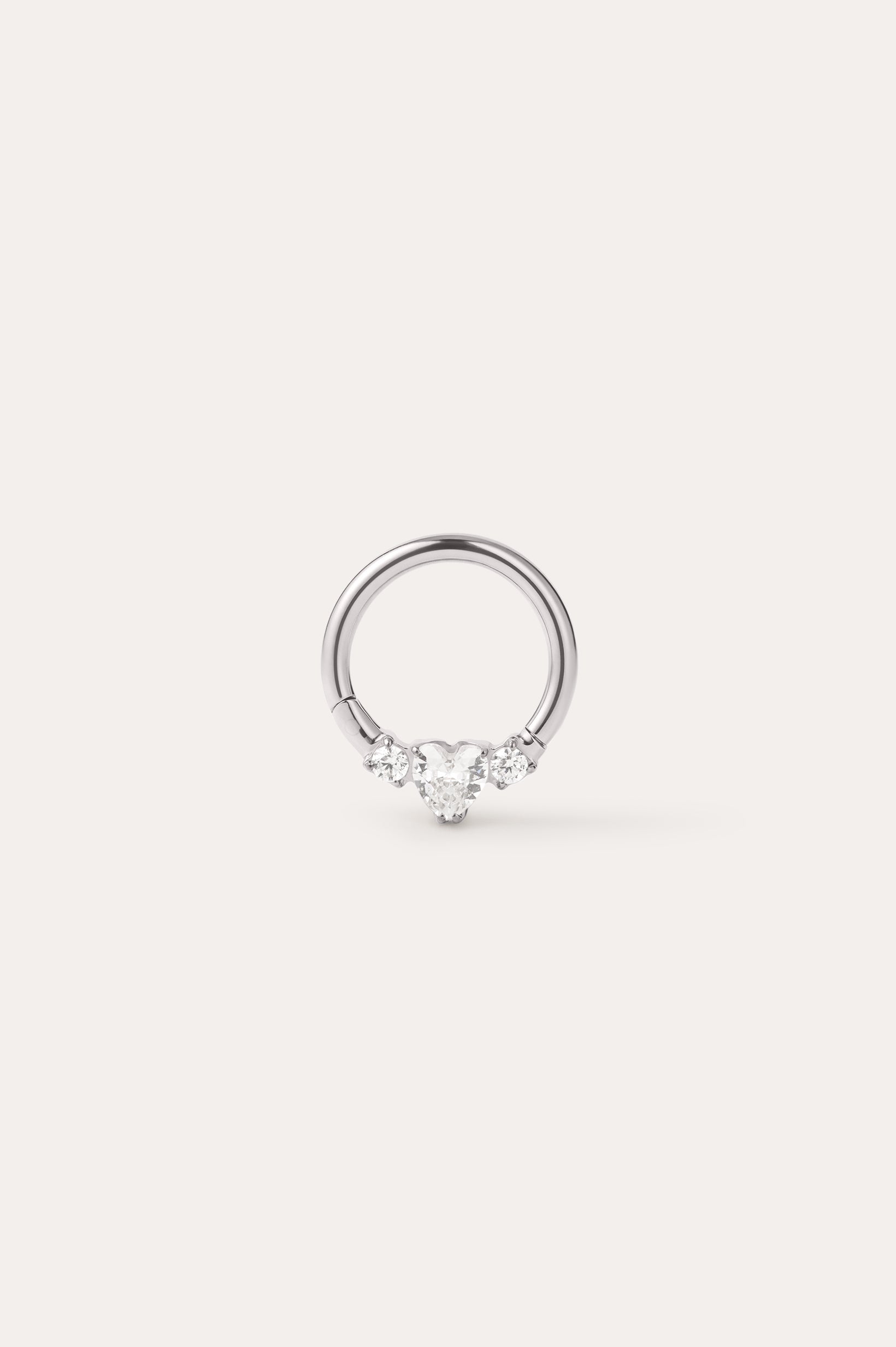 A Crystal Heart Titanium Daith Ring in Platinum, featuring a central heart-shaped gemstone flanked by two smaller round gemstones on each side, displayed on a plain light background. Crafted from implant-grade titanium with a platinum PVD finish, this hypoallergenic daith ring combines elegance with comfort for everyday wear.