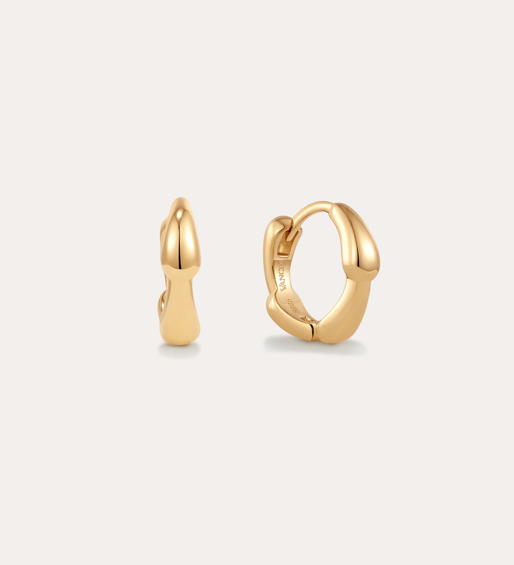 The Colette Droop Link Huggie Earrings in Gold feature smooth, rounded organic curves, showcased against a plain light background.