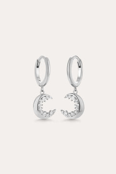 Crescent Moon Crystal Charm Huggies in Silver feature dangling crescent moon charms with sparkling cubic zirconia, shown on a light background.