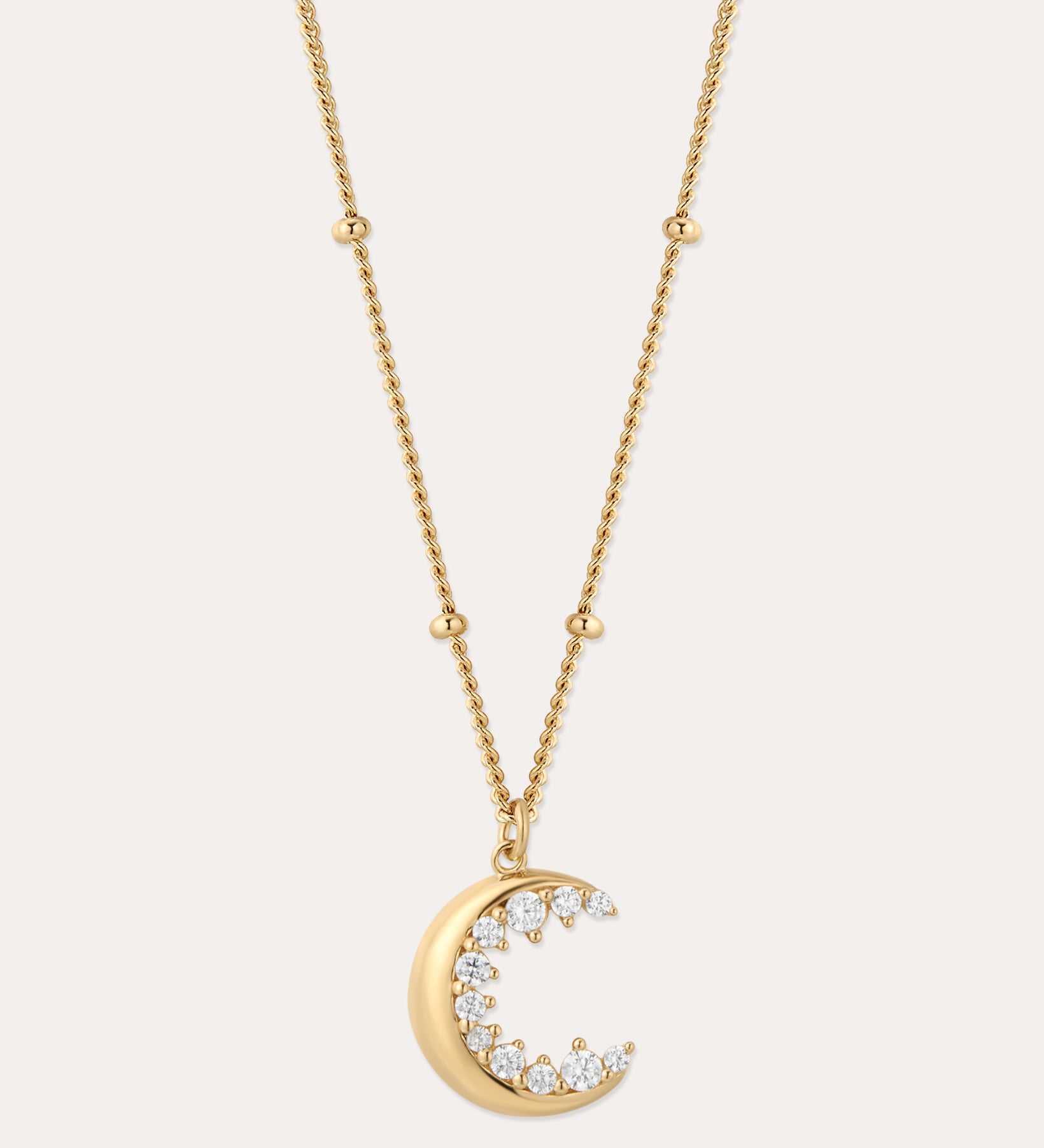 The Crescent Moon Crystal Charm Beaded Necklace in Gold features a beaded chain and a crescent moon pendant with sparkling clear stones, shown against a simple light background.