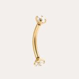 The Crystal Titanium Rook Barbell in Gold features a curved yellow gold PVD design with clear gemstones in prong settings at both ends, displayed against a simple light background.