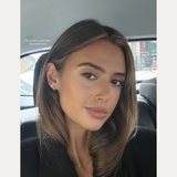 A young woman with straight brown hair and natural makeup sits in a car’s backseat, wearing a black top and a 14K Solid Yellow Gold Lab-Grown Diamond Trinity Flat Back Stud. Text above reads, “SPOTTED ON: DANI OLIVIA NEWMAN.”.