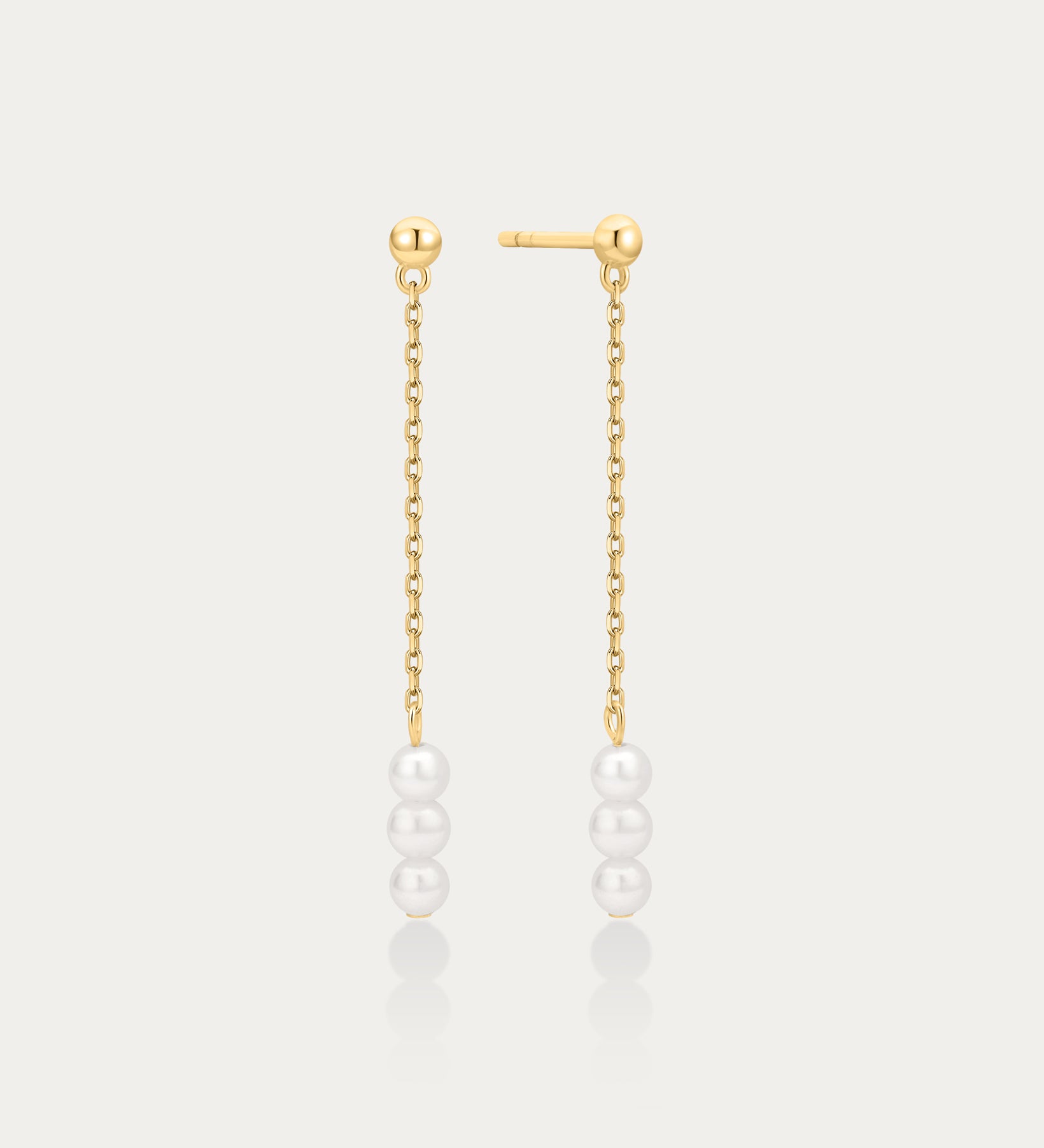 Gold chain earrings with pearls on a light gray background