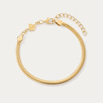 The Estelle Herringbone Chain Bracelet in Gold is a 3mm bracelet with an adjustable clasp, extension chain, and a small flat charm, perfect for bracelet stacking and shown on a light background.