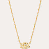 The Defender Evil Eye Necklace in Gold features an 18k gold-plated eye-shaped pendant with a central cubic zirconia and four dangling crystals, shown on a plain white background.