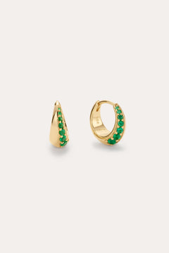 The Georgie Crystal Knife Edge Huggie Hoop Earrings in Green feature small gold hoops with a row of green crystals along the front, shown against a plain light background.