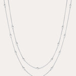The Simona Double Chain Stacking Necklace in Silver features two delicate layers with small, evenly spaced beads along each chain, shown against a light background.