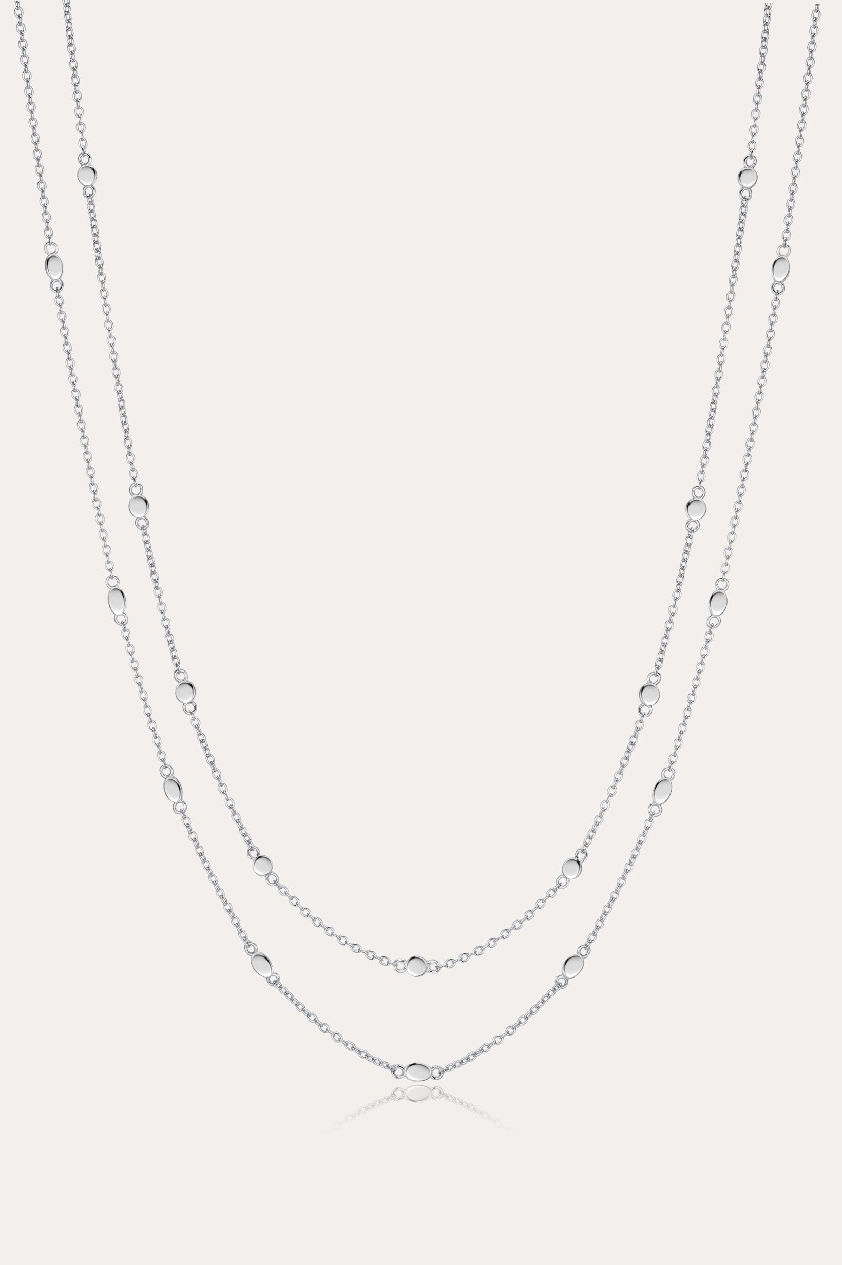 The Simona Double Chain Stacking Necklace in Silver features two delicate layers with small, evenly spaced beads along each chain, shown against a light background.