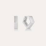 The Judith Hexagon Angular Huggies in Silver, featuring a chunky geometric design, are shown on a plain light background—one upright and one open to reveal the clasp. Perfect for stacking earring looks.