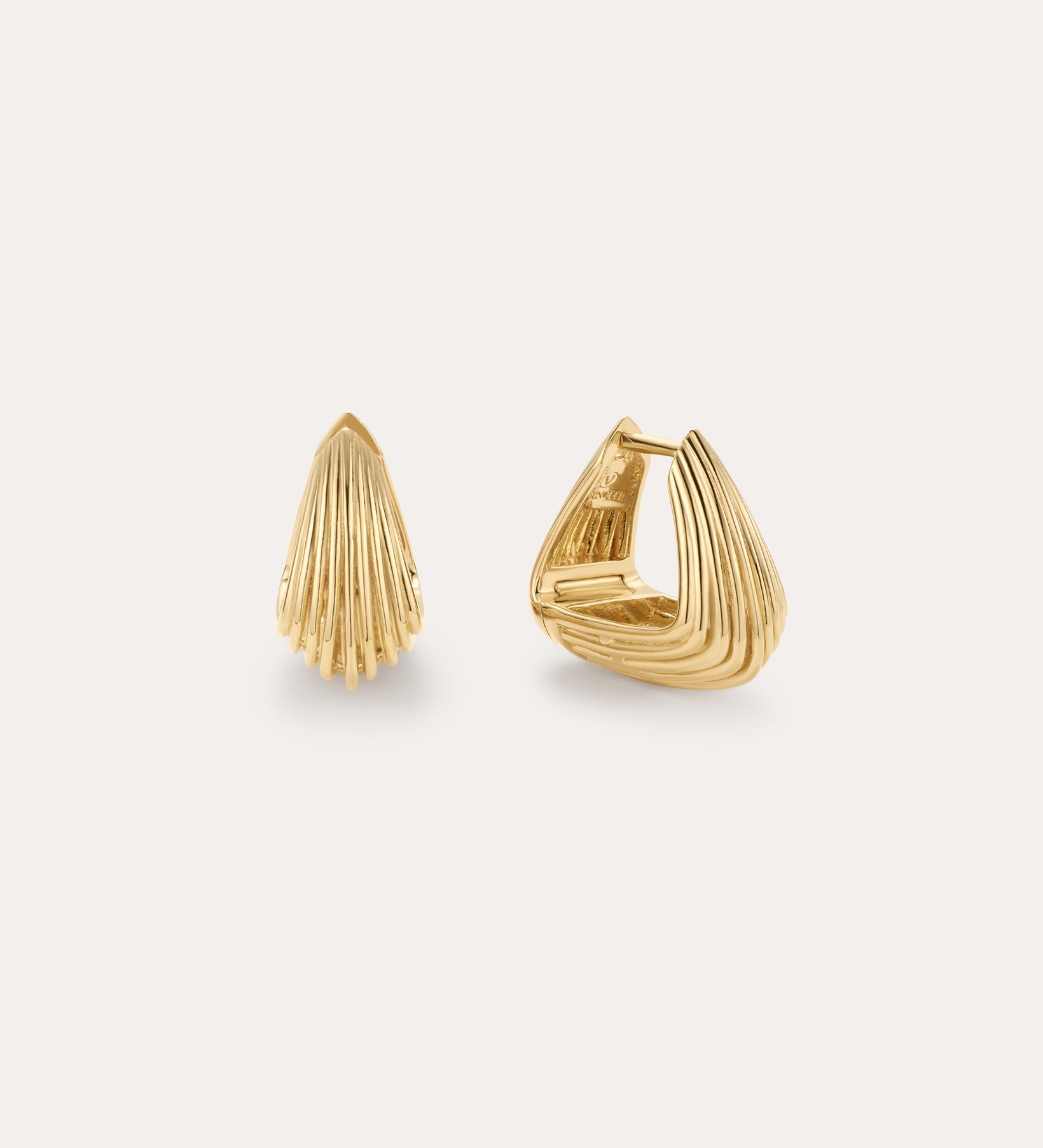 The Juno Ridged Chunky Hoops in Gold feature a modern, shell-inspired design. Displayed on a light background, one hoop stands upright while the other is open to showcase the clasp.
