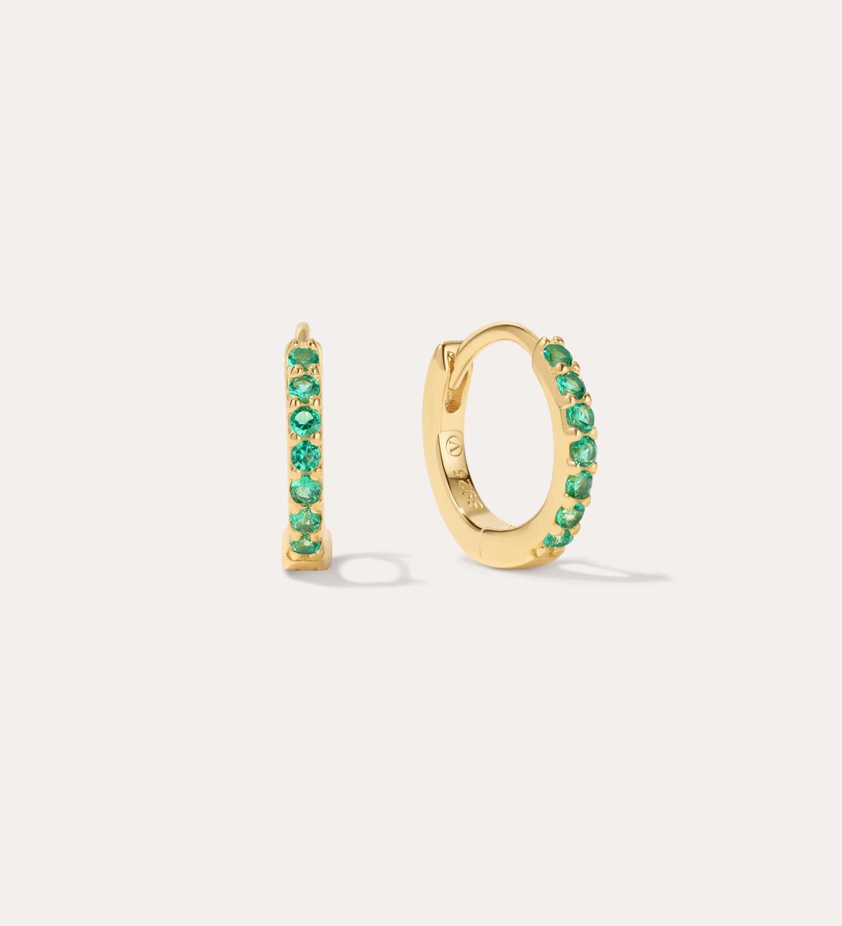 The Kiki Crystal Huggie Earrings in 18k Gold Plated/Green feature a row of green crystals on each earring, with one shown from the side and one from the front—versatile, stylish options for daily wear.