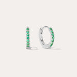 The Kiki Crystal Huggie Earrings in Sterling Silver/Green are displayed on a white background, with one earring facing forward and the other shown from the side.