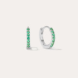 The Kiki Crystal Huggie Earrings in Sterling Silver/Green are displayed on a white background, with one earring facing forward and the other shown from the side.