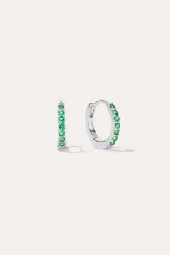 The Kiki Crystal Huggie Earrings in Sterling Silver/Green are displayed on a white background, with one earring facing forward and the other shown from the side.