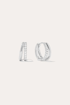 The Kira Crystal Double Hoop Huggies in Sterling Silver are shown, each featuring a row of sparkling round crystals along the front edge. The background is plain and light-colored.