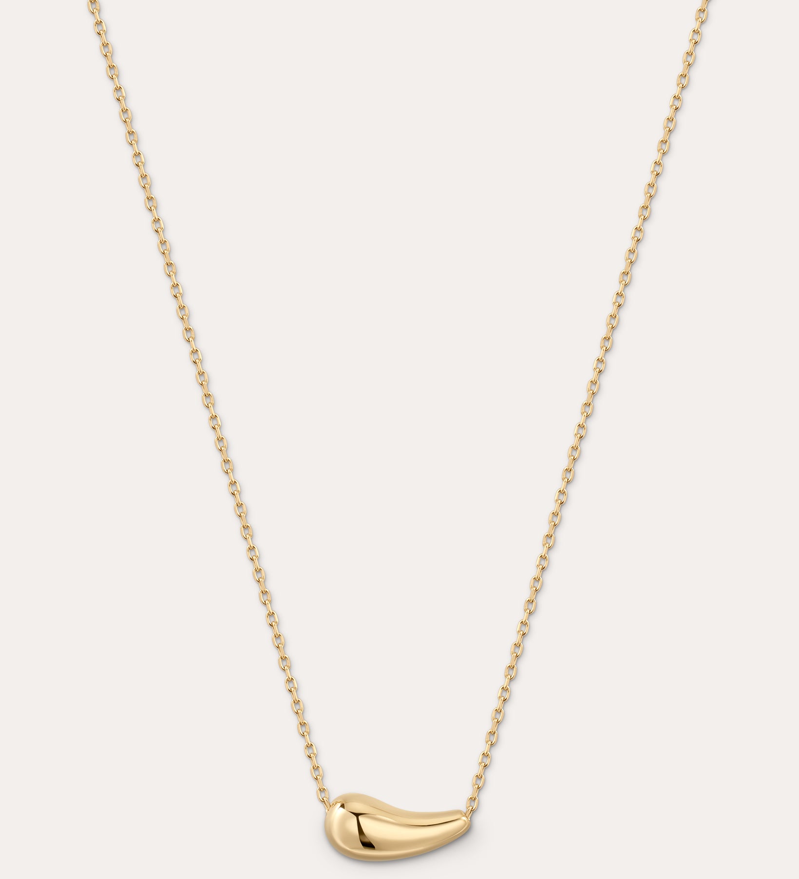 Gold necklace with a small pendant on a light gray background