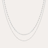 The Mini Paperclip Double Chain Necklace in Silver features two sterling silver layers: an upper chain with elongated oval links and a lower chain with smaller, closely connected links for a simple, elegant look.