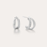 Nadine Pavé Twisted Stud Earrings in Silver feature lightweight, asymmetrical silver hoops with a row of sparkling stones along the inner curve, displayed on a plain white background.