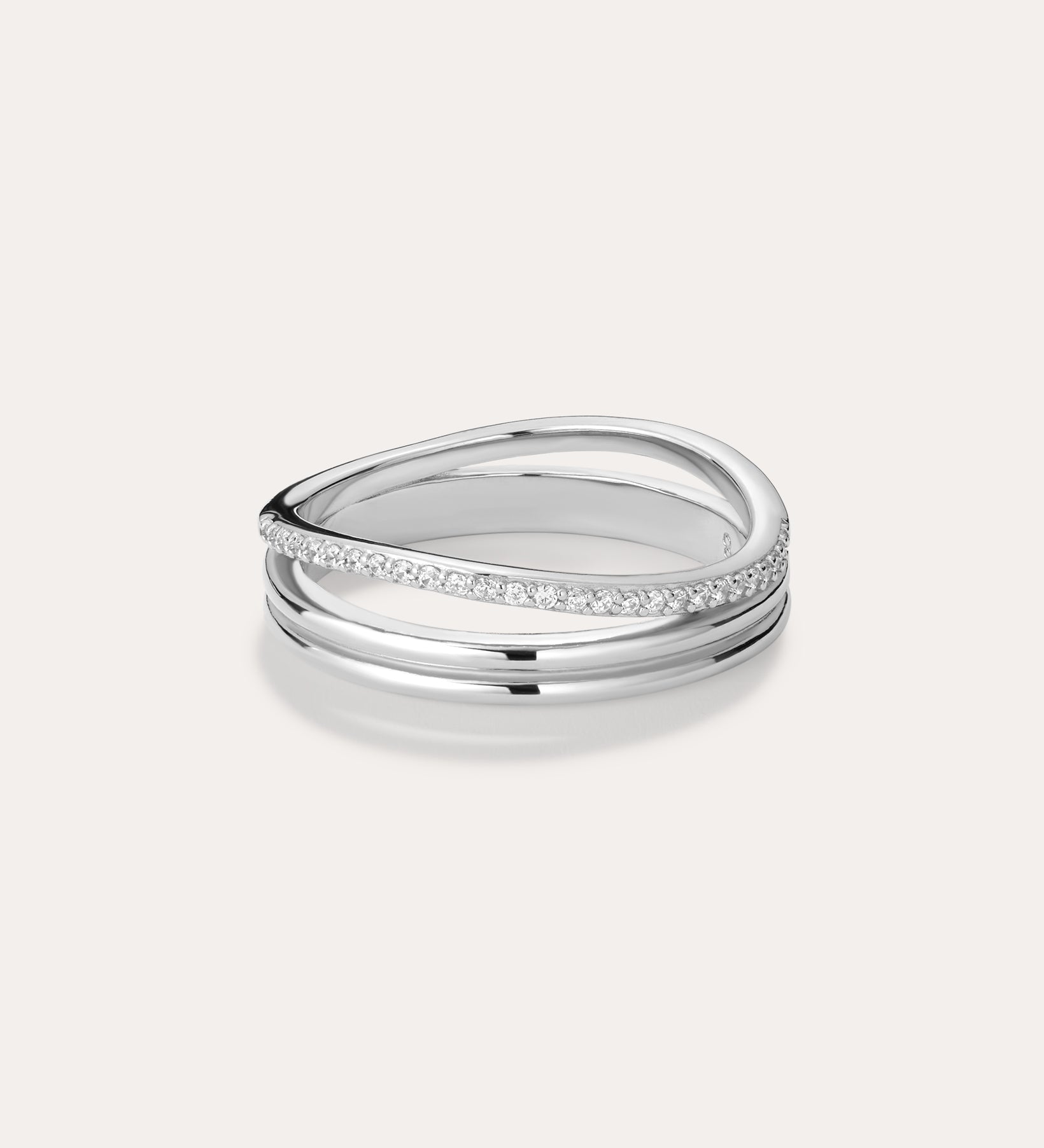 The Noor Pavé Triple Band Ring in Silver showcases a modern overlapping design with a polished finish and a row of sparkling pavé diamonds along one edge, elegantly set against a light background.