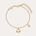 The Nora Double Pendant Bracelet in Gold features an adjustable clasp, a gold heart charm, and a teardrop-shaped cubic zirconia pendant for subtle sparkle.