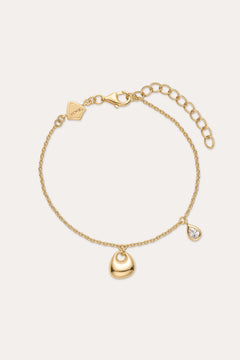 The Nora Double Pendant Bracelet in Gold features an adjustable clasp, a gold heart charm, and a teardrop-shaped cubic zirconia pendant for subtle sparkle.