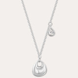 The Nora Double Pendant Necklace in Silver features a fine chain with a shiny sculptural pendant and a separate tiny teardrop charm set with a clear cubic zirconia, displayed against a plain background.
