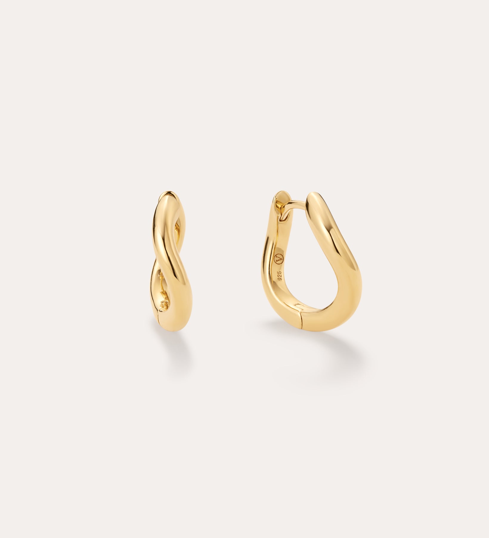 The Nori Twisted Hoop Earrings in Gold, featuring an 18k gold-plated, organically twisted design, are displayed on a plain light background—one shown from the front and one from the side to highlight their fluid curves.