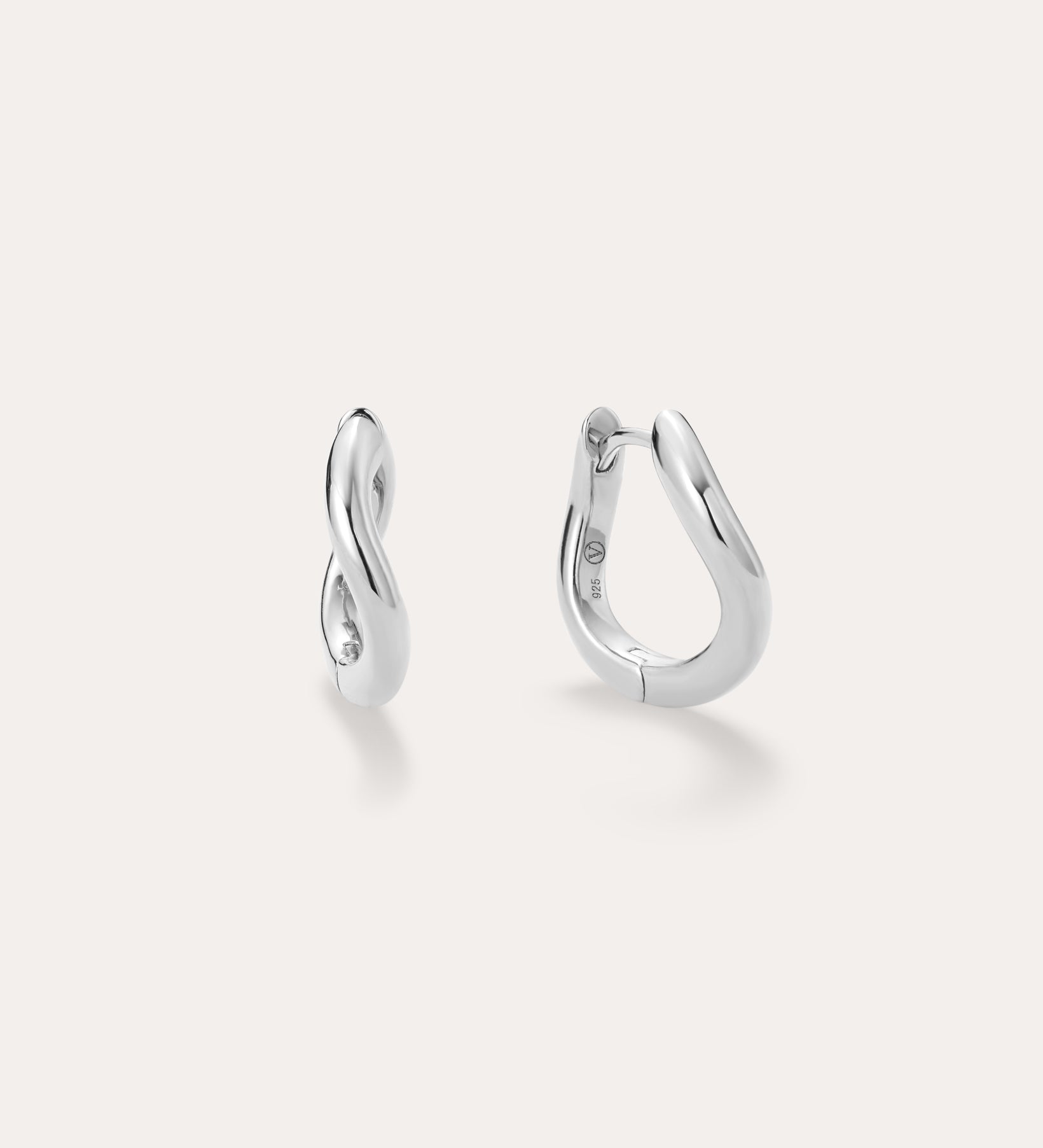 A pair of small, polished Nori Twisted Hoop Earrings in Silver with an infinity-like twist design, displayed on a light background. One sterling silver hoop faces front; the other is sideways to show the clasp.