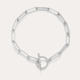 The Paperclip Toggle Bracelet in Silver features elongated oval links and a circular toggle clasp, displayed on a plain light background.