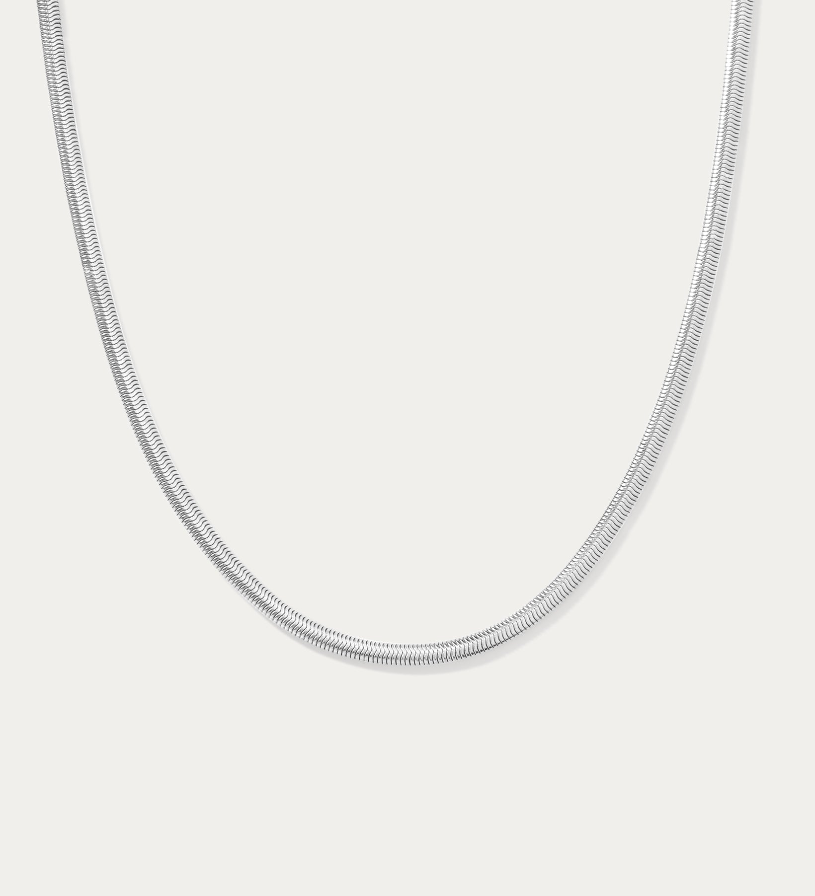 The Estelle Herringbone Chain Necklace in Silver is a sleek, minimalist chain shown against a plain white background.