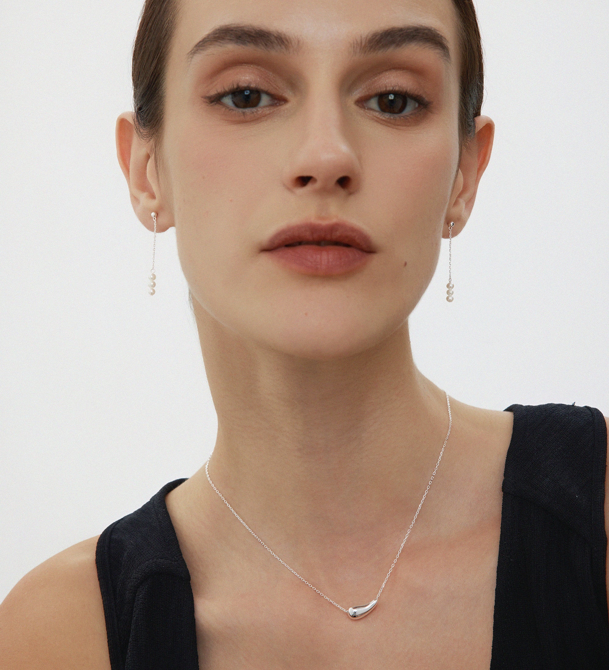 Woman wearing a delicate necklace with a plain background