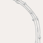 The Simone Triple Chain Layered Bracelet in Silver features three delicate sterling silver chains adorned with small round and oval disc accents, finished with a lobster clasp closure.
