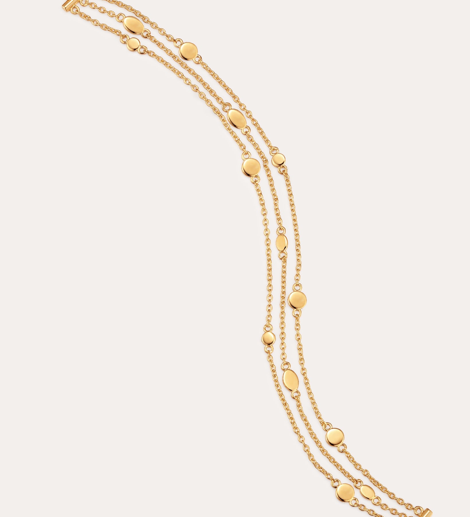 A triple layered gold bracelet with chain links and small circular embellishments, fastened with a lobster clasp.