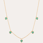 Thea Green Heart Pendant Gold Necklace features five small green cubic zirconia hearts evenly spaced on an adjustable gold chain, shown against a plain light background.