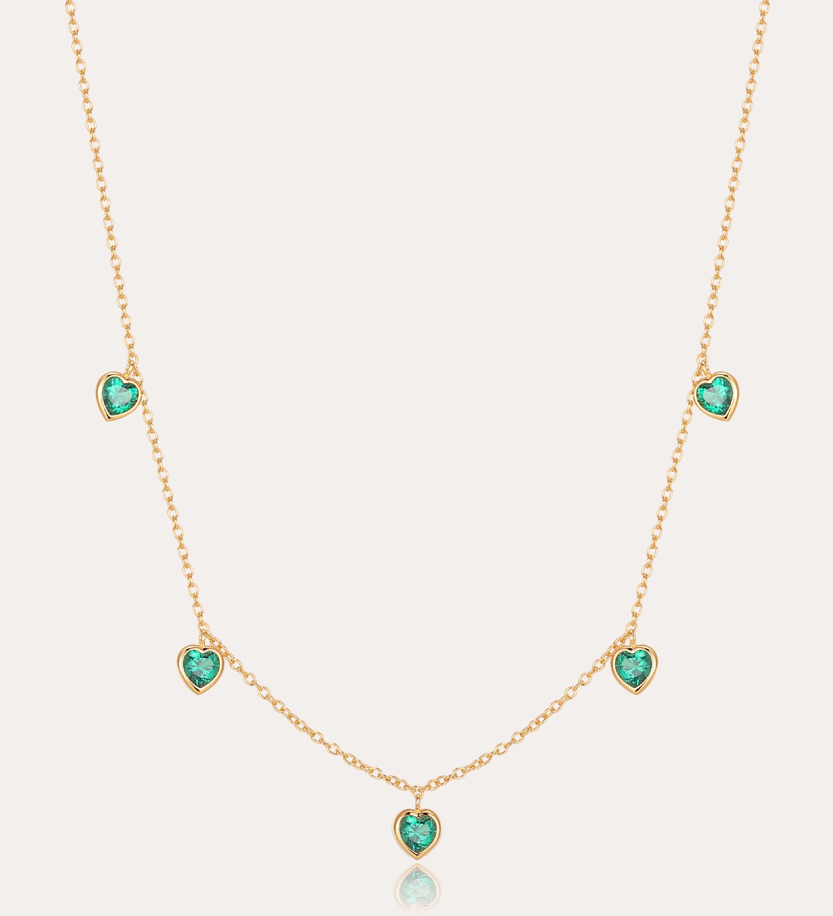 Thea Green Heart Pendant Gold Necklace features five small green cubic zirconia hearts evenly spaced on an adjustable gold chain, shown against a plain light background.