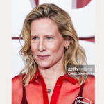 A woman with wavy blonde hair wears Juni Pavé Chunky Huggie Earrings in Gold and a sheer red blouse at an event. Text reads: SPOTTED ON: THEA SHARROCK – LADIES FIRST PREMIERE. A Getty Images watermark is visible.