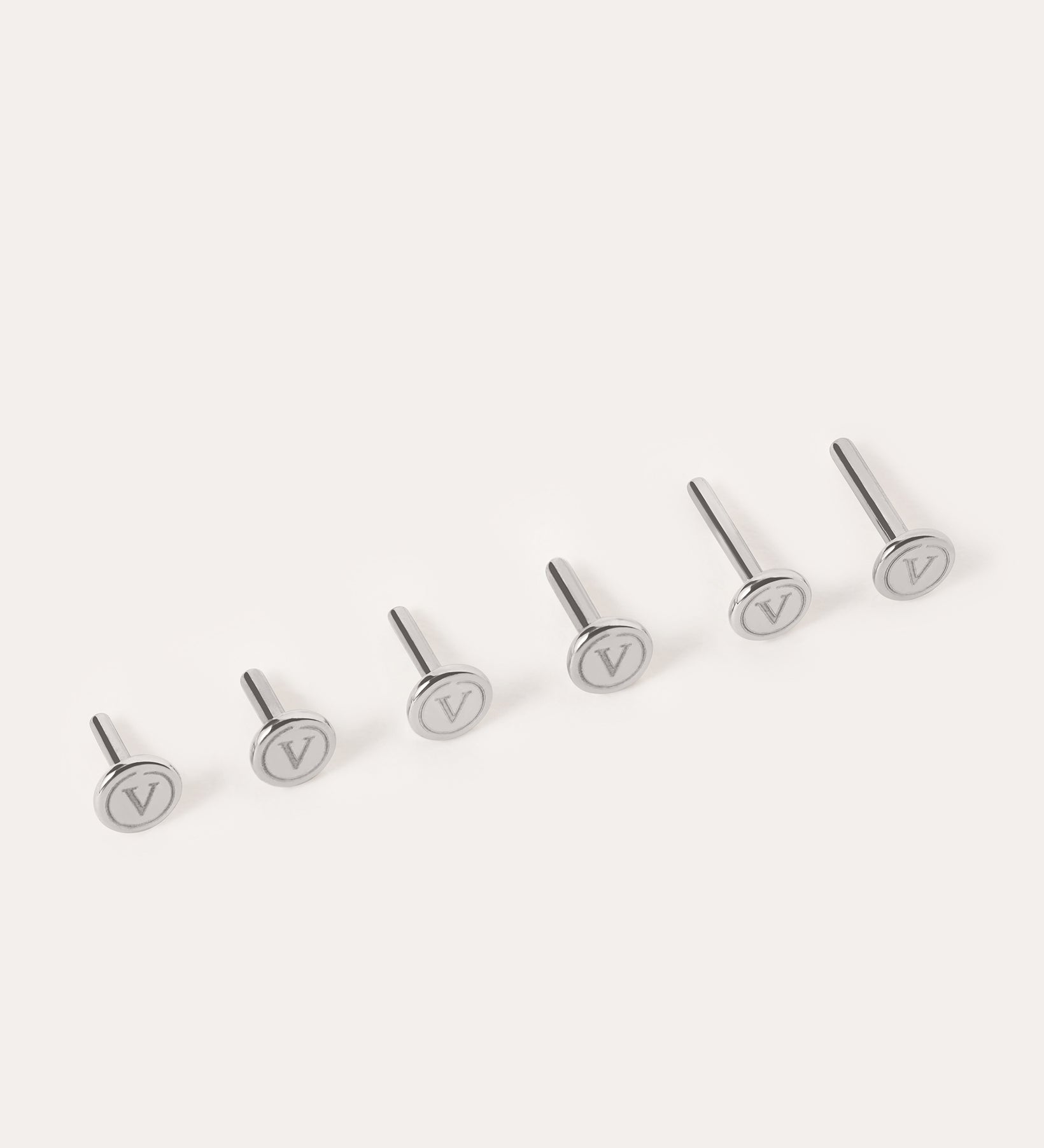 Six silver metal pins—Push-Pin Titanium Flatback Replacement Backings—are arranged in a row on a light background. Each flat circular top is engraved with a V symbol, highlighting the sleek craftsmanship of Vanchi titanium.
