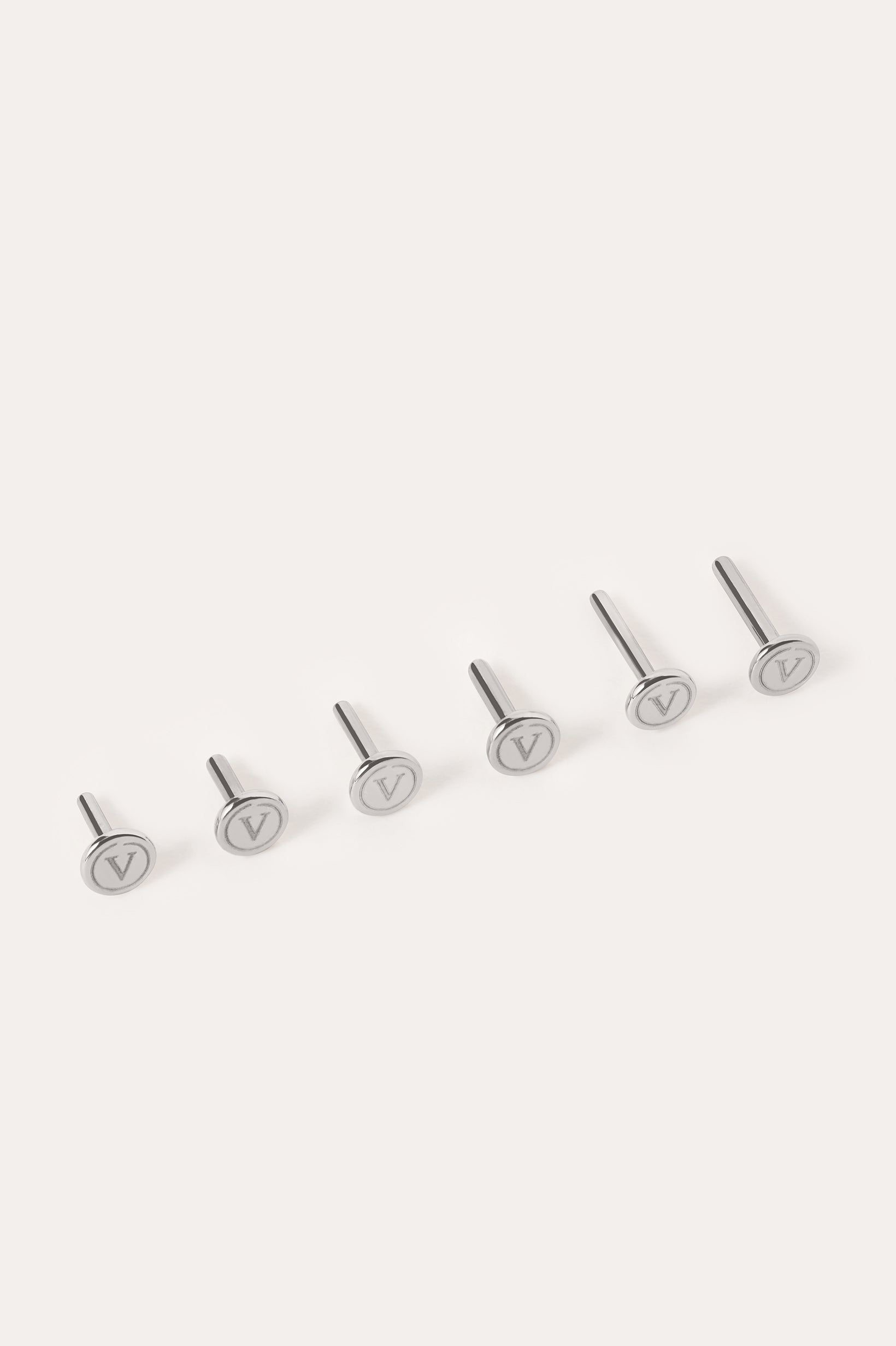 Six silver metal pins—Push-Pin Titanium Flatback Replacement Backings—are arranged in a row on a light background. Each flat circular top is engraved with a V symbol, highlighting the sleek craftsmanship of Vanchi titanium.