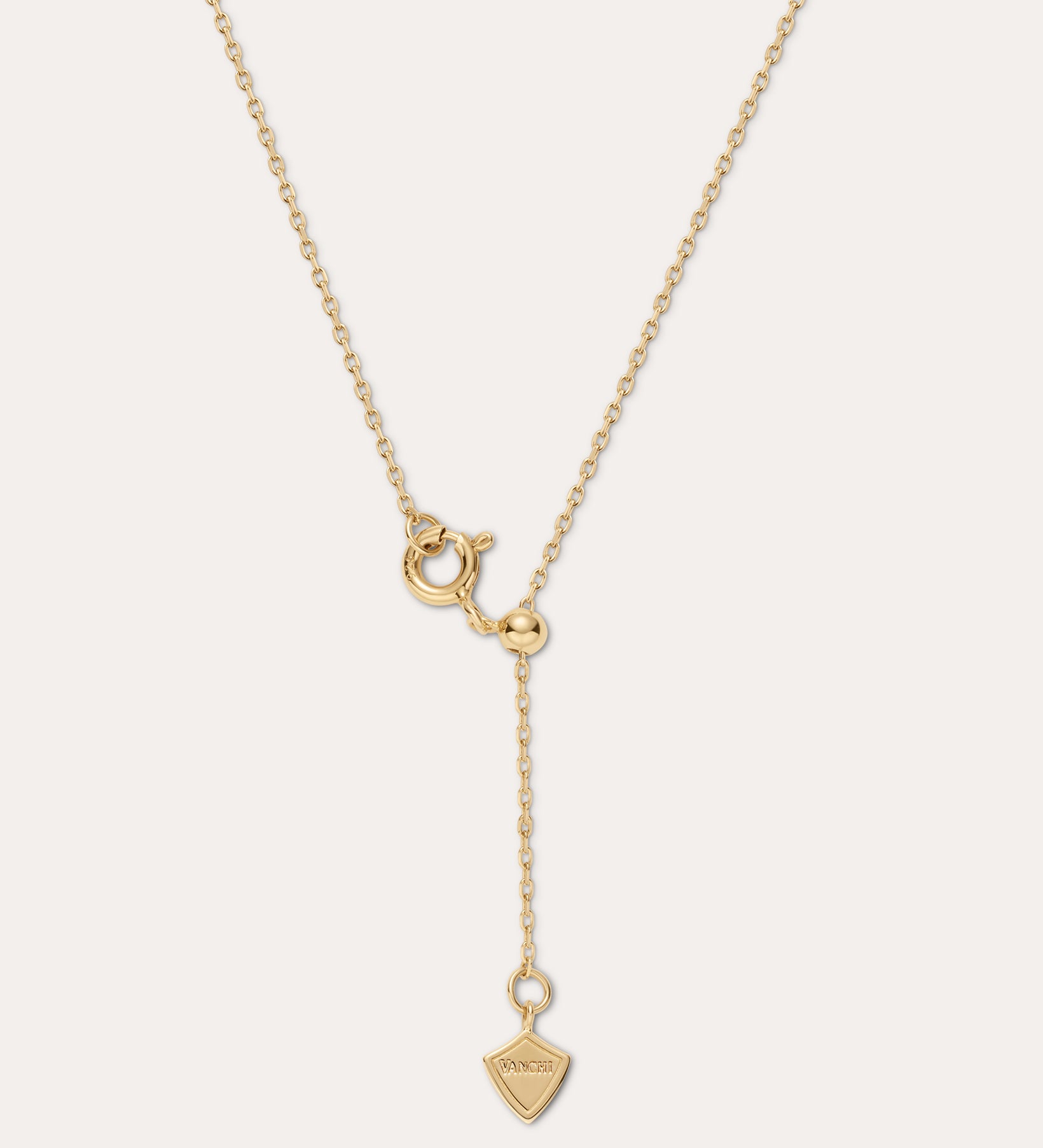 Gold necklace with a unique pendant on a light beige background
